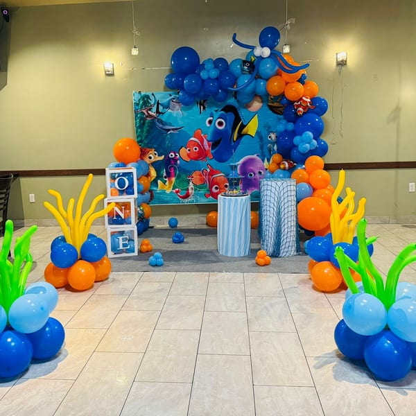 A Finding Dory themed birthday party setup with blue and orange balloons and character backdrop.